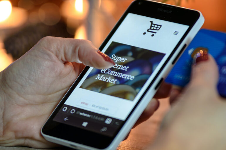 Persoon shopt via haar telefoon met de creditcard bij de hand.