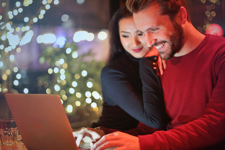 Man en vrouw zoeken cadeaus achter laptop