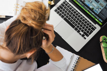 Gestresste vrouw met haar laptop en andere werkmaterialen.