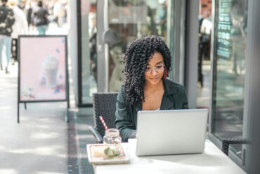 Persoon werkt met laptop aan restauranttafeltje in de zon