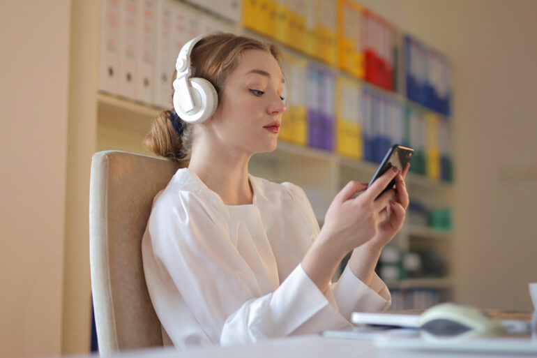 Persoon houdt telefoon vast zittend aan een bureau
