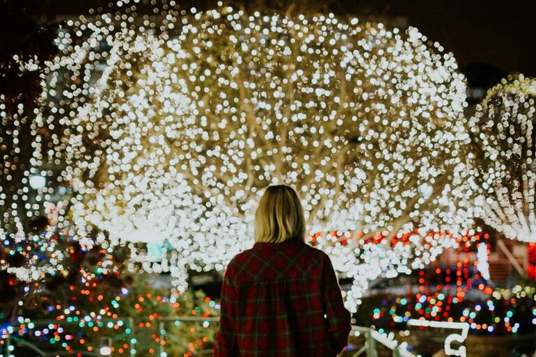 Vrouw loopt tussen kerstverlichting door