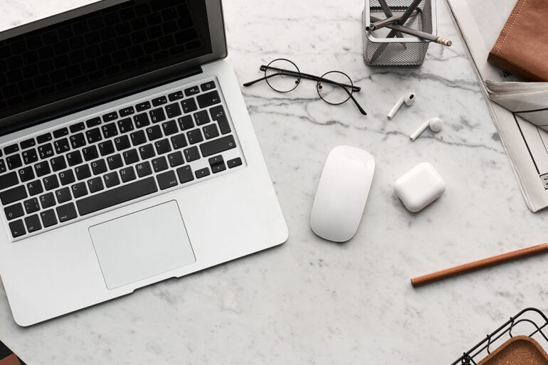 Flat lay met macbook, bril, earpods