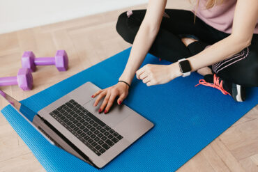 Vrouw volgt sportles via de laptop