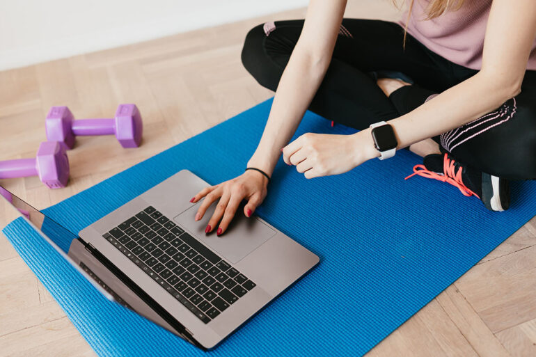 Vrouw volgt sportles via de laptop