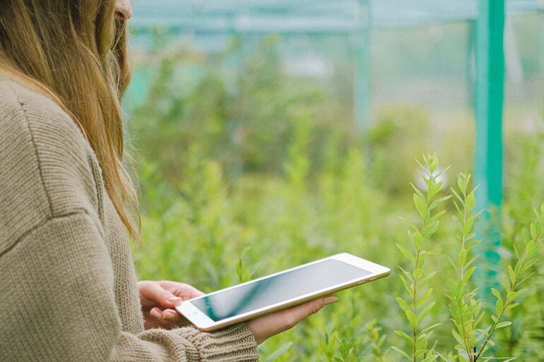 Vrouw met Ipad in tuin
