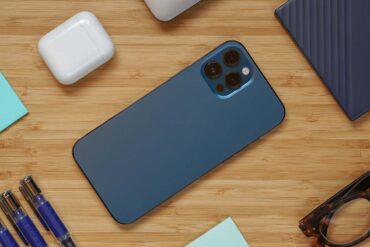 iPhone 12 Pro Max op een bureau omgeven door andere technologie en kantoor elementen