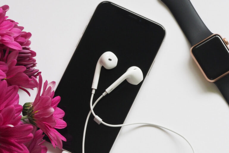 Close Upfotografie Van Oortelefoons Bovenop Iphone 6 en smartwatch Dichtbij Bloemen