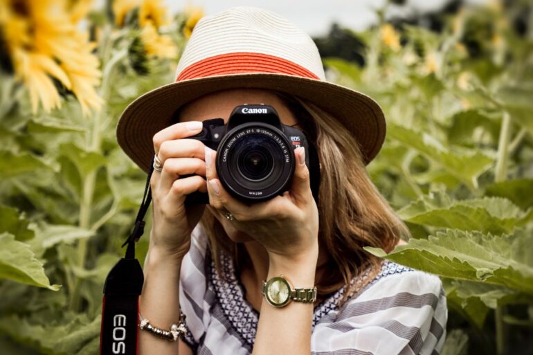vrouw met camera tussen zonnebloemen