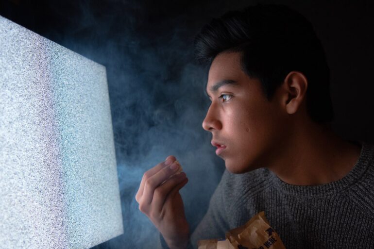 man die popcorn eet terwijl hij tv kijkt