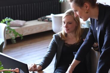 wee-vrouwen-die-op-zwarte-laptopcomputer-gebruiken