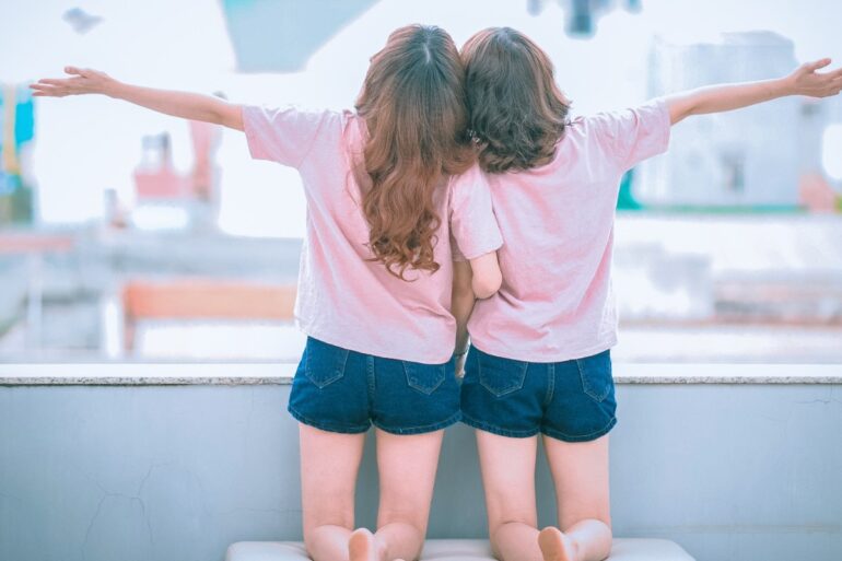 twee-meisjes-samen-knielen-armen-verspreiden