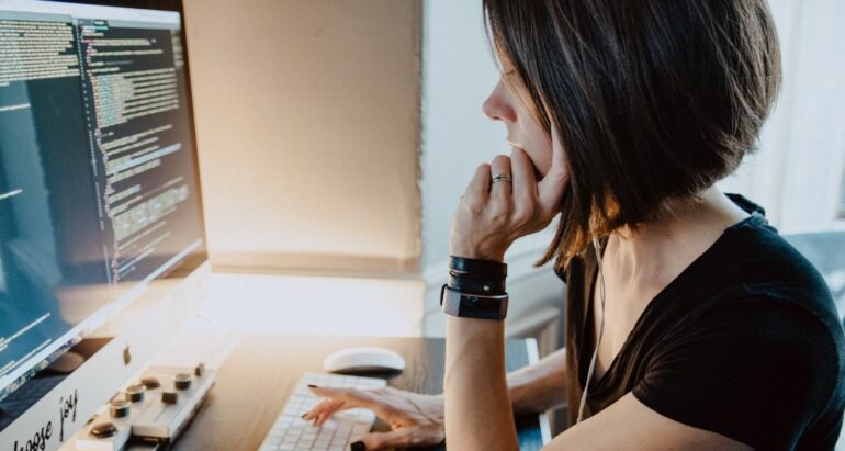 Woman sitting at a desk in front of coding computer screen