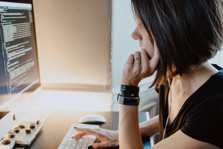 Woman sitting at a desk in front of coding computer screen