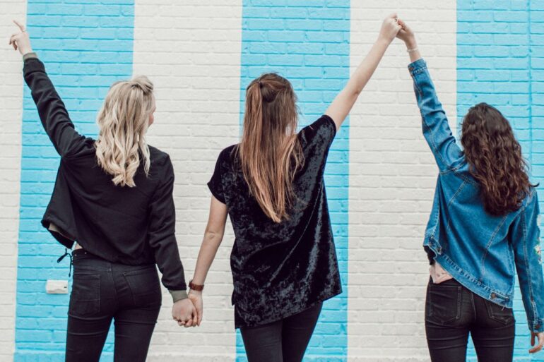 3 vrouwen die ellkaars handen vasthouden